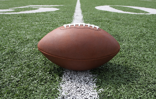 A football laying on the 50 yard line football on the 50 yard line